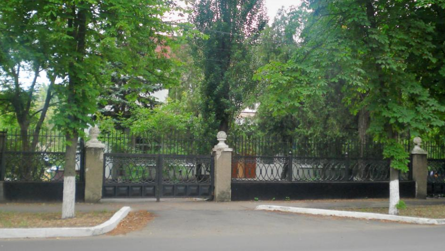 Двоповерхова будівля Новокаховського СБУ знаходиться за цими деревами